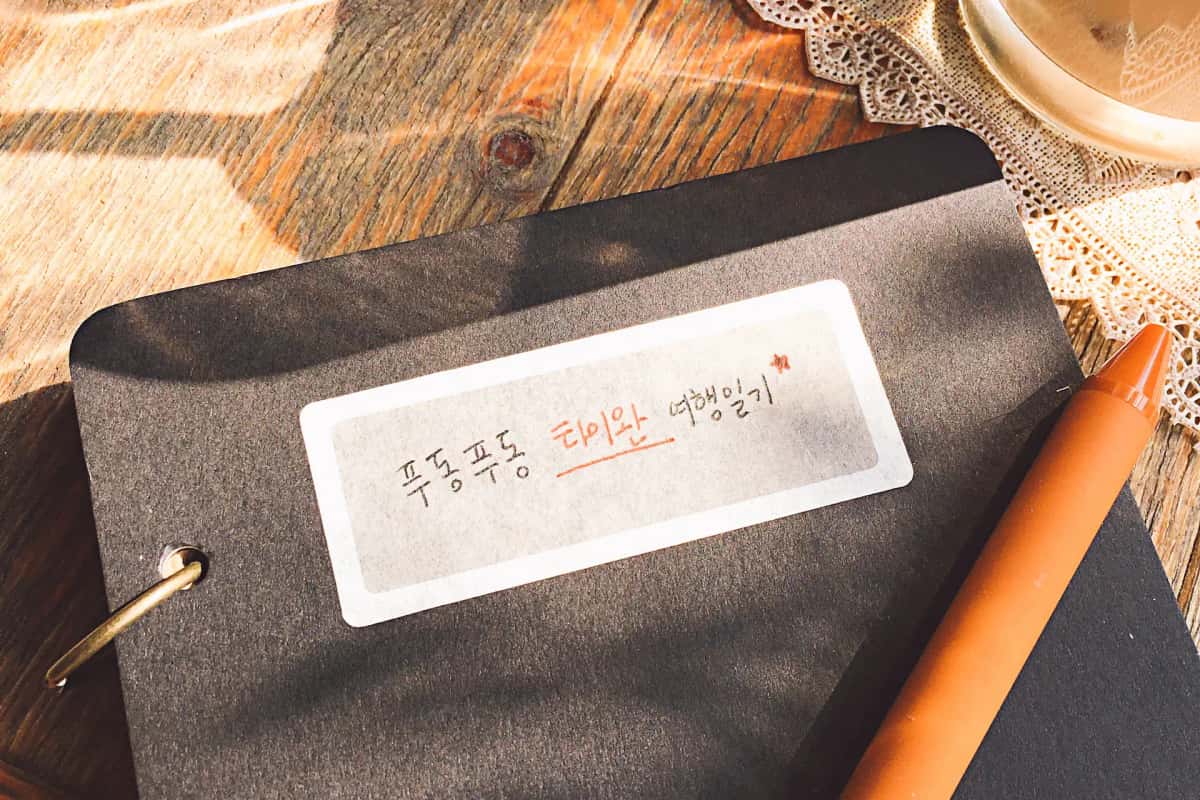 Carnet annoté à la main en hangeul, l'alphabet coréen, posé sur une table en bois